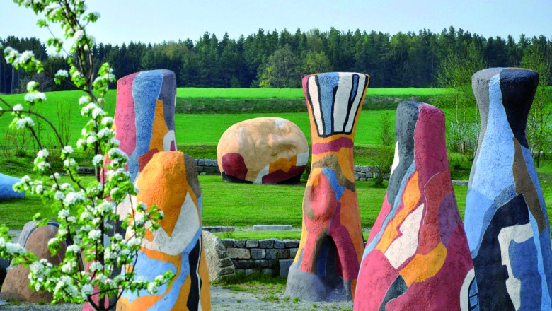 Kunstmuseum, © IDEA Bunte Skulpturen in einer grünen Landschaft mit Bäumen im Hintergrund.