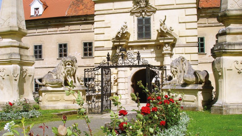 Schloss Greillenstein, © Schloss Greillenstein Eingang von Schloss Greillenstein mit Löwenstatuen und blühenden Rosen im Vordergrund.