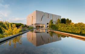 Modernes Geb&auml;ude der Loisium WeinWelt mit reflektierendem Wasserbecken im Vordergrund.