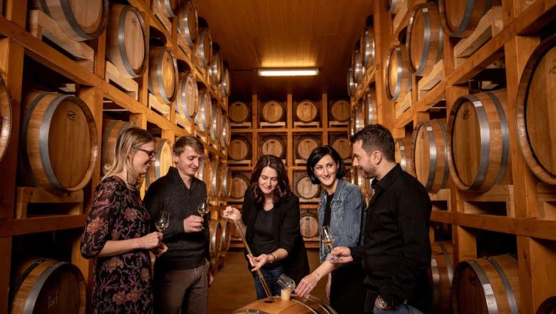 Gruppe von Menschen in einer Whisky-Destillerie, umgeben von Holzf&auml;ssern.