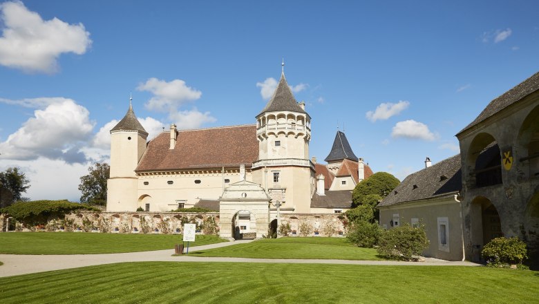Schloss Rosenburg mit T&uuml;rmen und gepflegtem Rasen unter blauem Himmel.