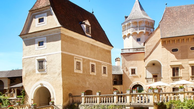 Historische Burg mit Türmen und Zinnen unter blauem Himmel.