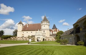 Schloss Rosenburg mit T&uuml;rmen und gepflegtem Rasen unter blauem Himmel.